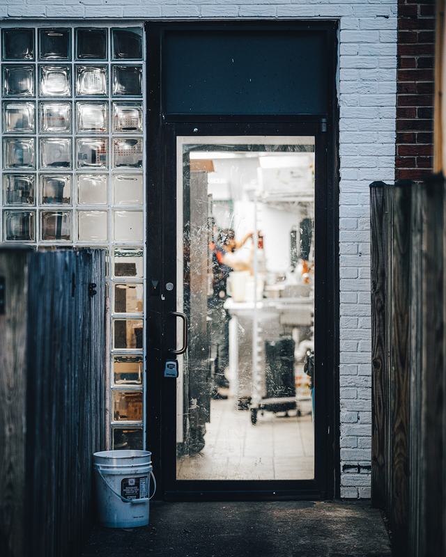 Zwarte deur met een stalen kader en glas in een bakstenen gevel